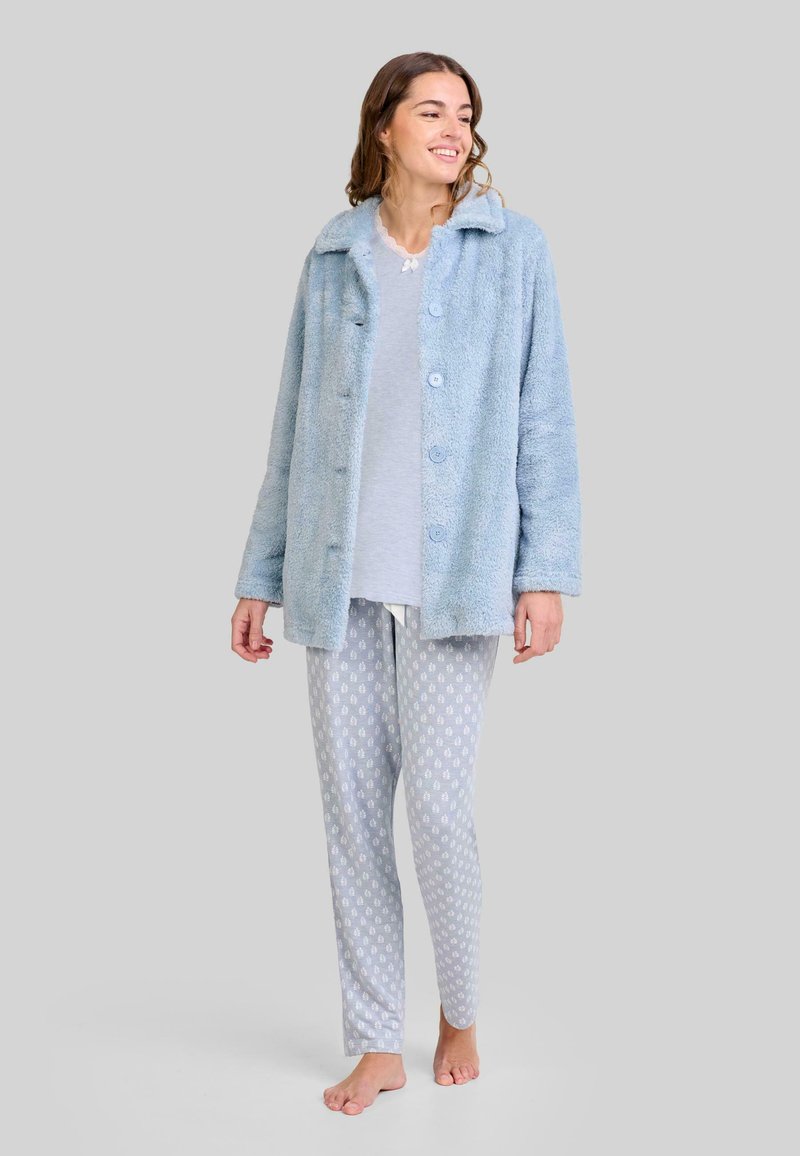 Chaqueta de felpa azul clara con cuello tipo solapa y cierre de botones, combinada con pantalones de pijama ligeros de color gris con estampado. Textura suave en toda la prenda.