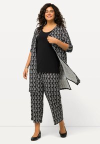 Kimono de estampado en blanco y negro, sobre una camiseta negra y pantalones a juego con el mismo estampado. El conjunto presenta un ajuste holgado y una tela ligera.