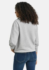 Grijze sweatshirt met een relaxte pasvorm, ribbelmanchetten en een zachte textuur, gecombineerd met marineblauwe jeans met een klassiek vijf-vakken ontwerp.