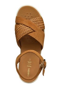 Sandalo in suede tan con cinturini intrecciati e suola bianca. Caratterizzato da una cinturino alla caviglia regolabile e una soletta perforata per la traspirabilità.