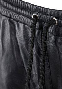 Schwarze Leder-Jogginghosen mit strukturiertem Finish, ausgestattet mit einem Kordelzug mit Metallösen und geflochtenem Band für eine verstellbare Passform.