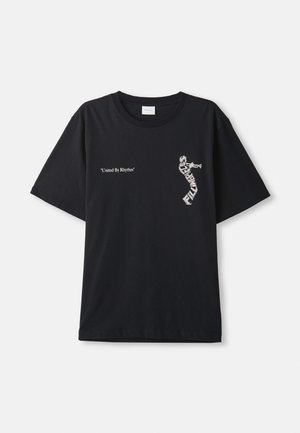 Svart bomull T-skjorte med oversized passform. Har hvit tekst "United By Rhythm" og grafisk design på fronten. Klassisk rund hals stil.