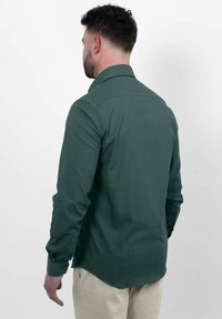 Donkergroene overhemd met lange mouwen, een kraag, achterste schoudernaad detail en een rechte zoom. Gemaakt van geweven stof met een gladde textuur.