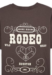 Maglietta in cotone marrone scuro con testo stampato bianco: "BRONC RIDING RODEO WILD WEST HOUSTON 1991" con disegni decorativi di corde.