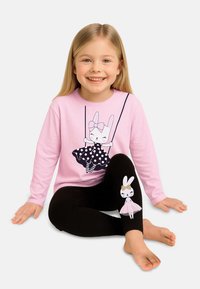 Ein pinkfarbenes Langarmshirt mit einem verspielten Hasenmotiv und einem gepunkteten Kleid. Schwarze Leggings haben ein Hasenmotiv am linken Bein.