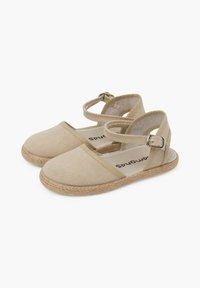 Espadrilles de lona beige con tirante en el tobillo, plantilla de yute, suela texturizada y detalles de costura mínimos. Adecuadas para uso casual.