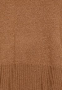 Bruine gebreide trui met een gladde textuur en geribbelde accenten aan de zoom. De stof heeft een constante, warme tint.