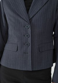 Navy pinstriped blazer with a tailored fit, notched lapels, four button closure, and two front pockets. Smooth fabric texture.