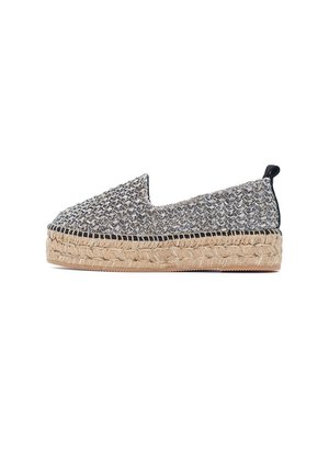 Slip-on espadrille met zwart-witte geweven bovenkant, dikke gevlochten jute plateauzool en zwart stoffen aantreklus bij de hiel.