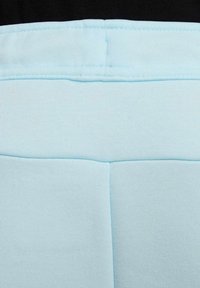 Fondo de tela azul claro con una superficie texturizada, que presenta una costura a lo largo de la parte superior y una sección inferior dividida por una línea horizontal.