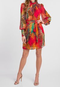 Färggör, knälång klänning med ett bälte att knyta. Tillverkad av lätt tyg, med starka nyanser av röd, orange och grön med ett leopardmönster.