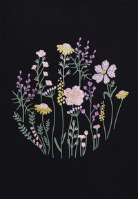 Un tejido negro presenta un diseño floral con varias flores en rosa, amarillo y púrpura, acentuado con purpurina para dar textura y detalle.
