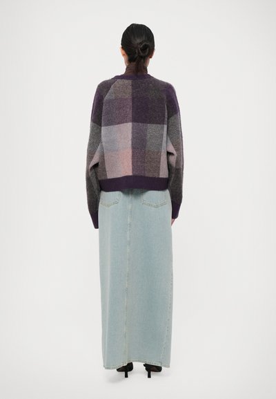 Purple checkered wool sweater with oversized fit and ribbed cuffs, paired with a long, light blue denim skirt and black heeled shoes.