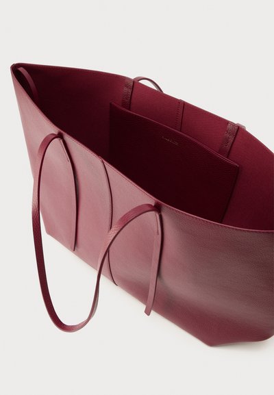 Τσάντα ώμου από βουργουνδικό δέρμα με μακριά λουριά, ανοιχτό πάνω μέρος και εσωτερικό με λεία υφή. Περιλαμβάνει μια μικρή τσέπη που ταιριάζει στο εσωτερικό.