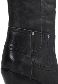 Bottillon en cuir noir avec une surface texturée, des coutures contrastées et des accents métalliques. Présente un talon courbé et une coupe ajustée.