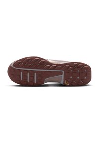 Sports shoe outsole featuring a textured brown rubber material with varying tread patterns and a gray midsole. Accents of gold are present.
