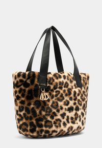 Tote bag van nep-bont met luipaardprint, voorzien van zwarte leren handvatten en gouden merksieraadjes aan de zijkant, tegen een effen achtergrond.