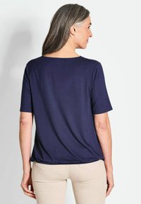 Marineblauw T-shirt met korte mouwen, gemaakt van zachte stof, met een ontspannen pasvorm en ronde halslijn, gecombineerd met lichtgekleurde strakke broek.