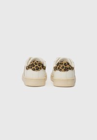 Vita sneakers med ett texturerat leopardmönstrat tyg på hälen. Har en gummisula och en slät läderkropp.