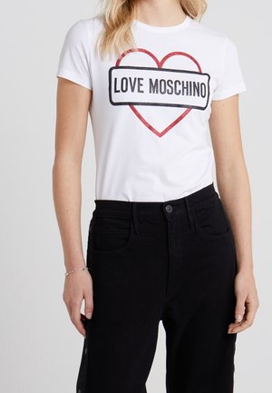 Person wearing a white t-shirt with a red heart and "LOVE MOSCHINO" text, paired with high-waisted black pants.