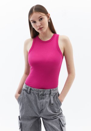 Top aderente senza maniche in tessuto a coste di un vivace rosa. Abbinato a pantaloni cargo grigi larghi con dettagli di bottoni e tasche.