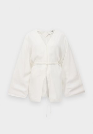 Blusa blanca estilo kimono con mangas anchas, escote en V, cinturón con nudo en el frente y detalle ligeramente abierto en la parte delantera.