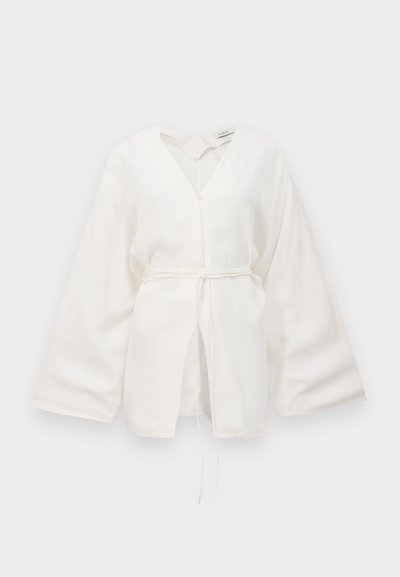 White kimono-style blouse with wide sleeves, V-neck, front tie belt, and slightly open front detail.