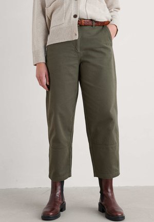 Pantalons verts olive en coton durable, avec une coupe droite, des coutures au genou et une texture lisse, associés à des bottines brunes.