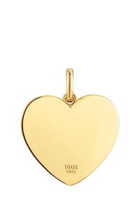 Colgante en forma de corazón chapado en oro con un acabado suave y un lazo superior para colgar, marcado con "TOUS" y "S925" en la parte trasera.