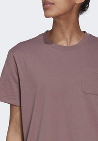 Krótki rękaw, lawendowy T-shirt wykonany z miękkiej bawełny. Posiada okrągły dekolt i prostokątną kieszeń na lewej piersi. Gładka tekstura.