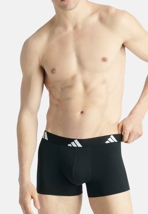Schwarze Boxershorts aus dehnbarem Stoff, mit einem breiten schwarzen Bund und weißen Adidas-Logo-Akzenten sowie einer enganliegenden Passform.