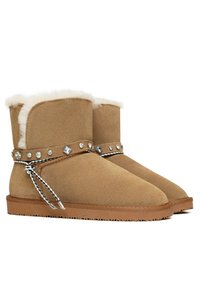Stivaletti alla caviglia in suede color tan con fodera in pelliccia sintetica, decorati con una cintura decorativa con borchie argentate e un'accenno di pizzo intrecciato.