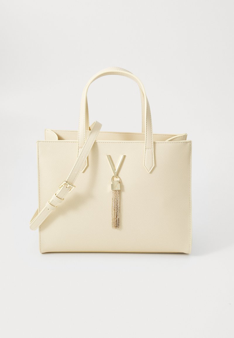 Beige faux leather handbag with a structured design, two top handles, a detachable shoulder strap, and a gold chain tassel detail.