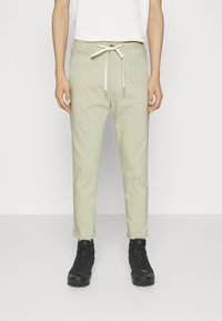 Hellgrüne, schmal zulaufende Jogginghosen aus weichem Stoff. Mit einem elastischen Bund mit Kordelzug und zwei Seitentaschen.