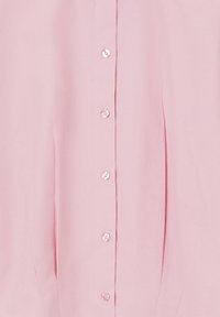Blusa rosa chiaro con chiusura frontale a bottoni lucidi, tessuto morbido e dettagli plissettati lungo i lati.