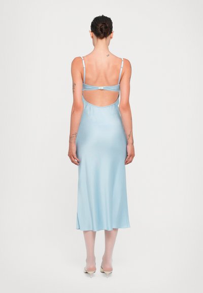 Vestido de satén azul claro con tirantes finos y espalda descubierta. La tela tiene una textura suave y el diseño llega hasta la mitad de la pantorrilla.
