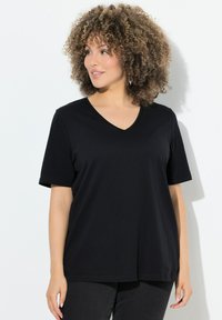 Zwarte, korte mouwen V-hals t-shirt van zacht materiaal, met een relaxte pasvorm en een gladde textuur, gecombineerd met donkere spijkerbroeken.