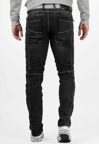 Zwarte denim jeans met een slim fit, met contrasterende witte stiksel, meerdere achterzakken en een ritszakdetail.