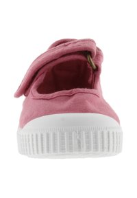 Scarpa da bambino in tessuto rosa con suola in gomma bianca, vista frontale, dotata di un cinturino pieghevole fissato da un anello metallico.