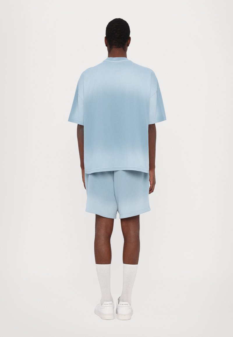 Helles blaues Set, kurzärmliges Hemd und Shorts. Weiche Textur, lockerer Schnitt, glattes Material mit subtiler Farbverlaufsübergang.