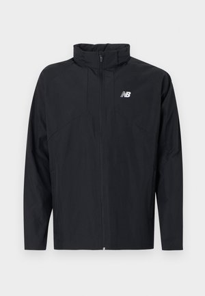 Czarna lekka kurtka na pełny zamek z wysokim kołnierzem i białym logo New Balance na lewej piersi.