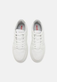 Hvite skinnsneakers med perforert tå, rund form og snøring. Har "HUGO" merke i rødt på tungen.