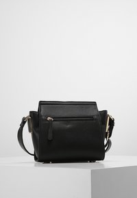 Black leather handbag with a textured finish, rectangular shape, front zip pocket, and adjustable strap. Gold-tone hardware accents.