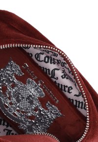 Interno di una borsa in pelle scamosciata rossa con una placca logo argentata, caratterizzato da un motivo testurizzato e una chiusura con zip con dettagli metallici.
