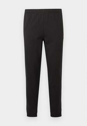 Μαύροι ελαστικοί παντελόνια με ψηλή μέση, στενή γραμμή και ρεβέρ στους αστραγάλους, παρουσιάζονται σε απλό φόντο, με μπροστινή όψη χωρίς τσέπες ή διακοσμήσεις.