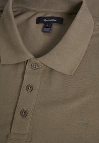 Khaki polo triko s límcem, třemi hnědými knoflíky a texturovanou tkaninou. Obsahuje malé logo v dolním rohu. Přiložena velikost L etiketa.