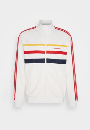 Giacca atletica zip bianca con strisce orizzontali rosse, gialle e blu navy. Presenta polsini e colletto a coste, con logo Adidas sul petto.