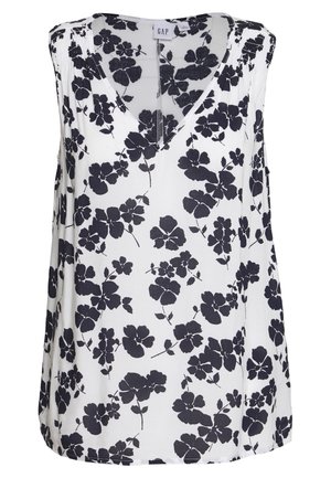 Blouse sans manches avec un décolleté en V, faite dans un tissu léger, arborant un fond blanc avec un motif floral noir.