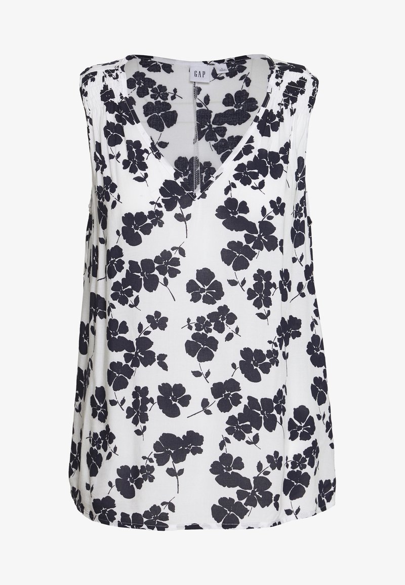 Blouse sans manches avec un décolleté en V, faite dans un tissu léger, arborant un fond blanc avec un motif floral noir.