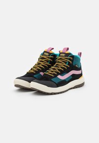 Zapatillas altas con parte superior de ante negro, acentos en azul verdoso, detalles en rosa y cordones dorados sobre una suela de goma blanca y marrón.